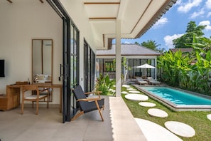 A modern outdoor living area with a pool, seating, and a view of the house. - Beta Villa by DH (Ubud)