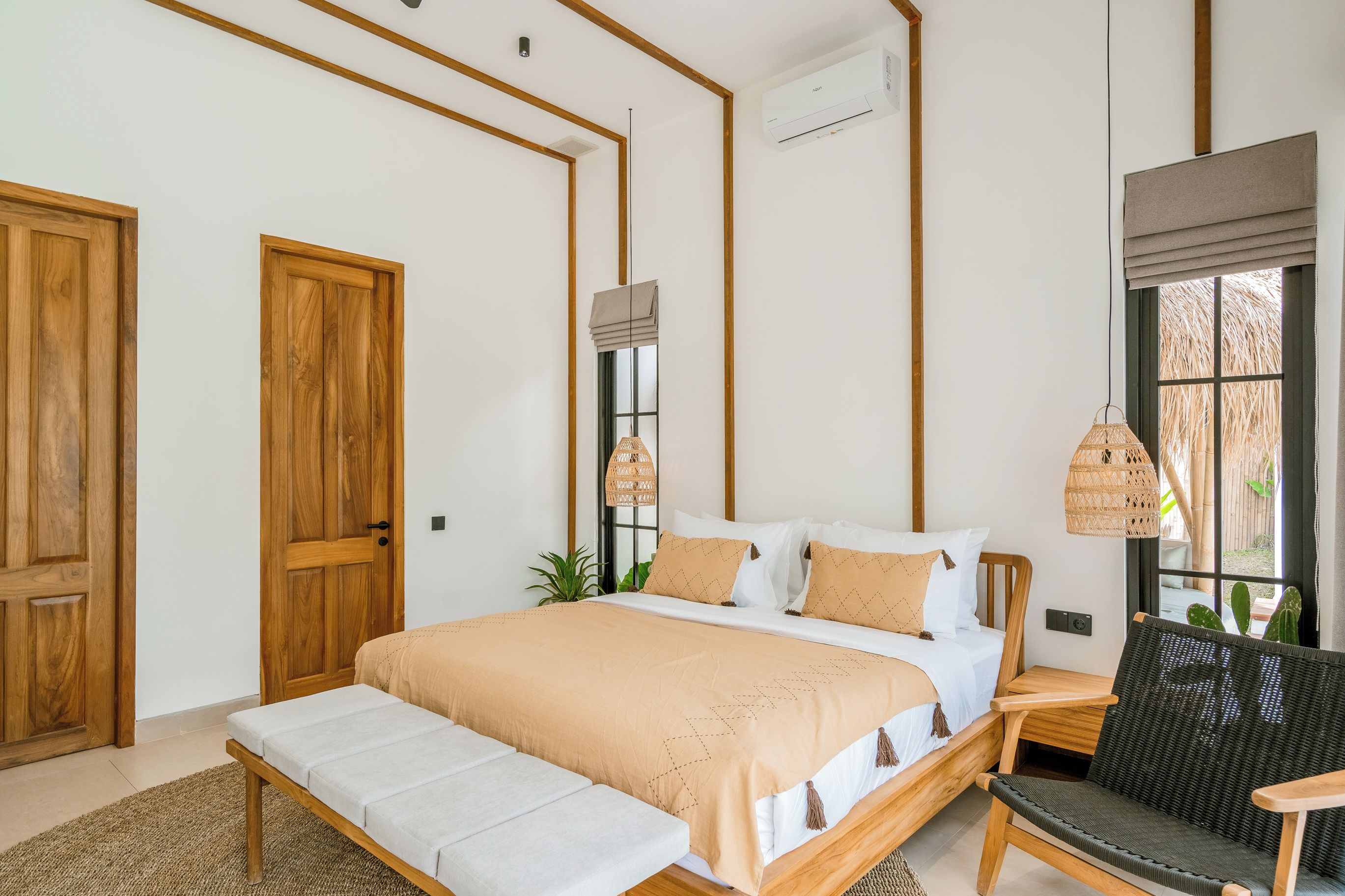 Une chambre à coucher avec un grand lit, des tables de chevet, un banc, une chaise et une fenêtre donnant sur un beau paysage.
