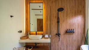 Une salle de bain moderne avec un meuble-lavabo en bois, un grand miroir, une douche à l’italienne et un lavabo.