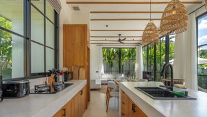 A modern kitchen with a central island, wooden cabinets, and large windows.