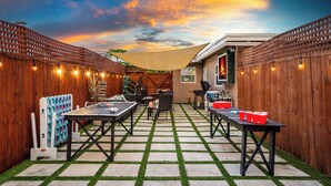 A patio area with tables and chairs, a wooden fence, and a string of lights.