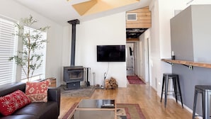 Una sala de estar moderna con chimenea, un televisor de pantalla plana y una escalera que sube a un nivel superior.