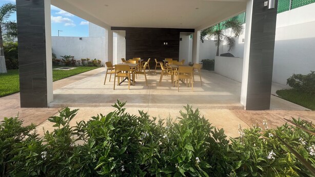 A covered outdoor dining area with a modern design, featuring a central table and chairs, surrounded by greenery and a clear sky. - Spacious Cancun Retreat • Pool • Sleeps 6 • Kid Friendly (cancun)