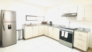 A kitchen with a refrigerator, microwave, stove, and cabinets. - Spacious Cancun Retreat • Pool • Sleeps 6 • Kid Friendly (cancun)