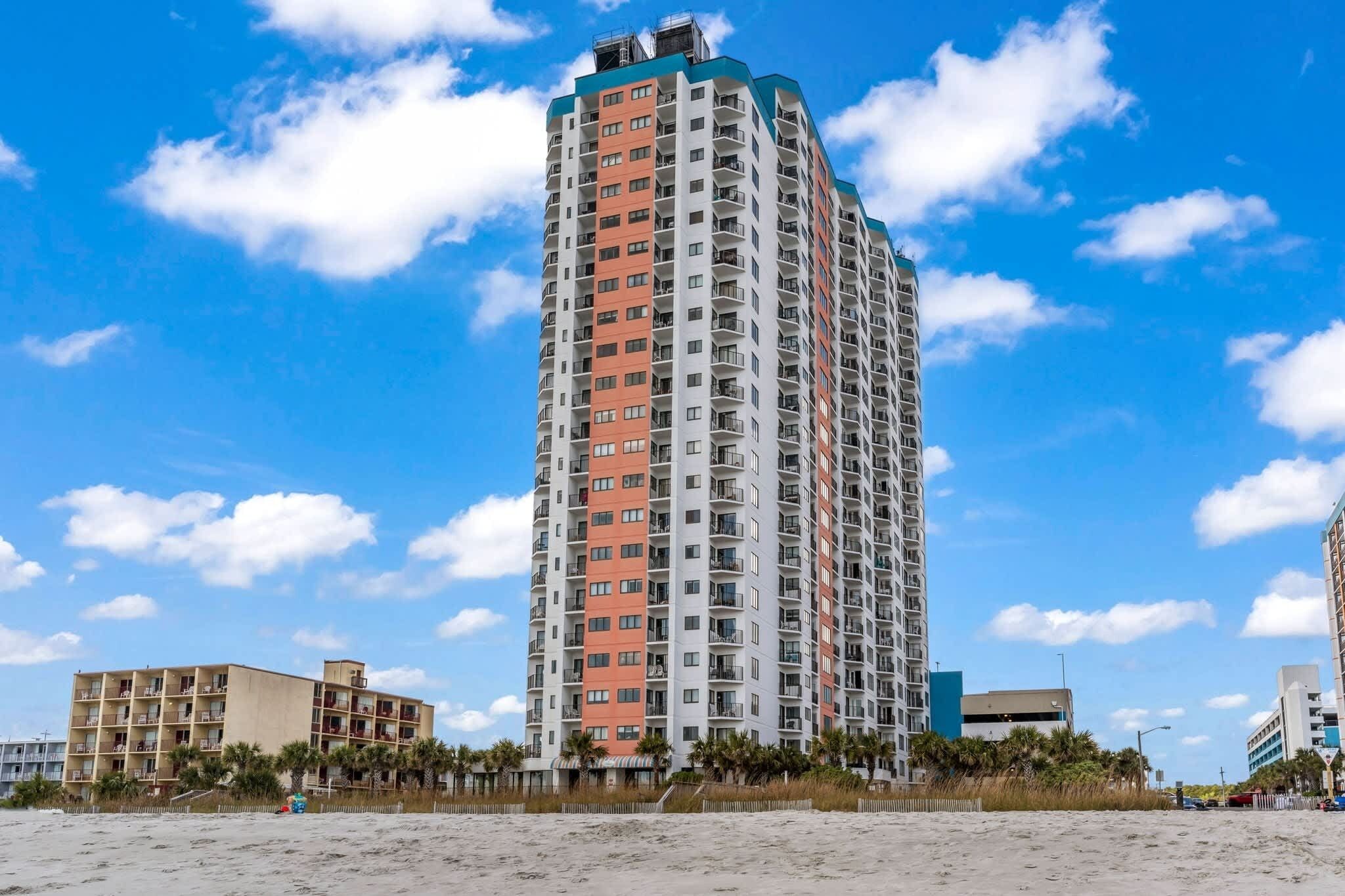 Un grand hôtel à étages, doté de balcons et offrant une vue sur la plage.