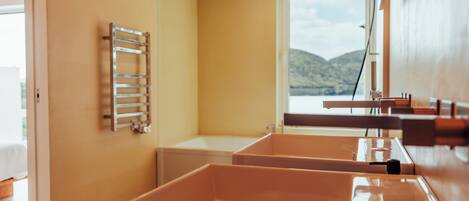 A bathroom with a bathtub, a towel rack, and a window with a view of hills.