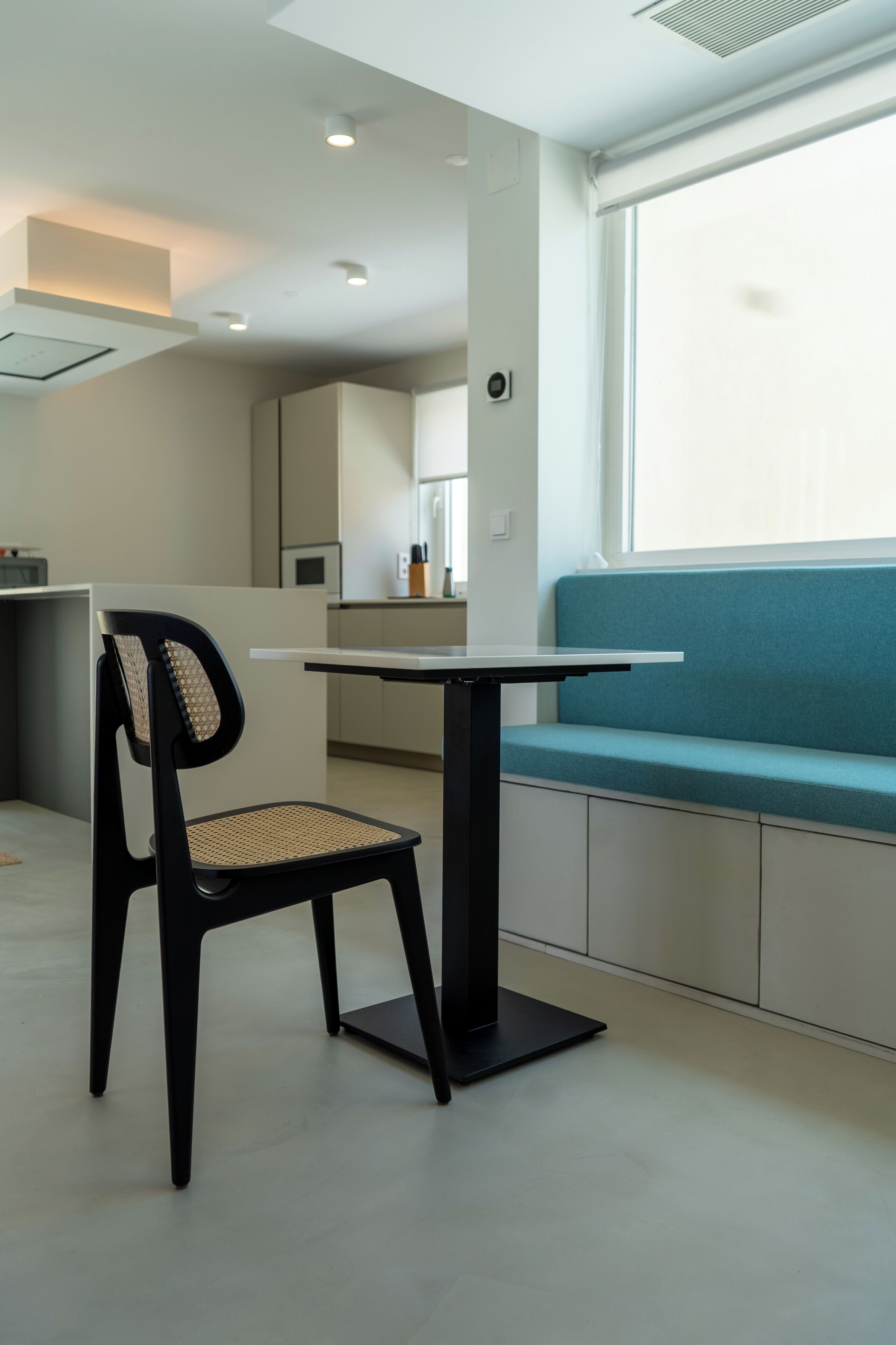 Una cocina moderna con zona de comedor, que incluye una silla negra, una mesa y un banco azul.