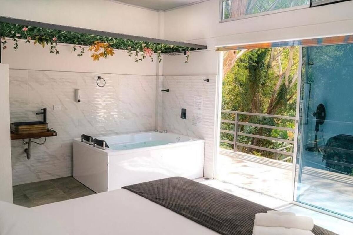 A modern bathroom with a large bathtub, a small sink, and a glass shower enclosure.