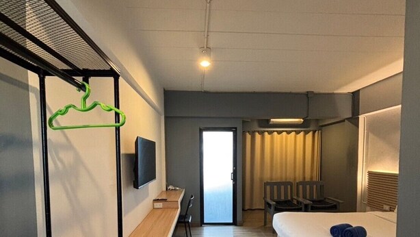 Une chambre d’hôtel avec un lit, un bureau, une chaise, une télévision et une fenêtre.