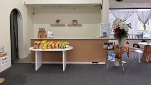 Un espace d’accueil avec un comptoir où sont exposés des en-cas et des boissons, un petit arrangement floral et un panneau d’information.