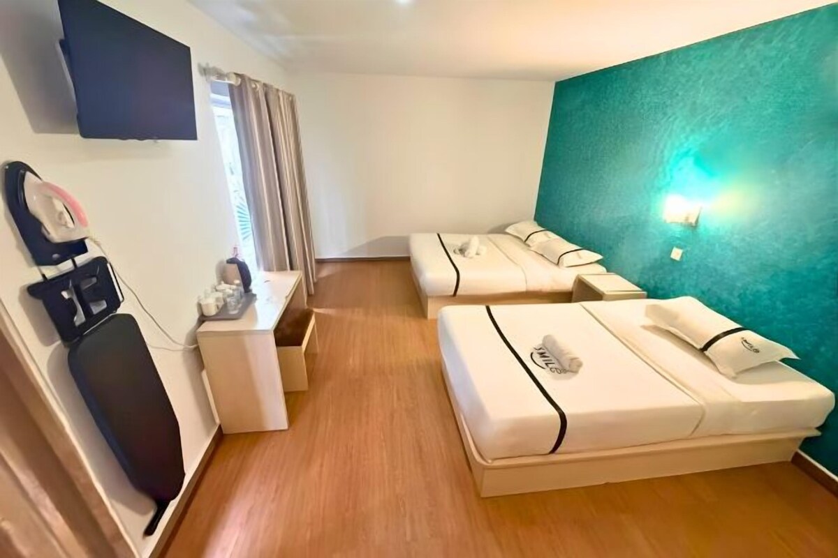 A hotel room with two beds, a desk, a chair, and a TV mounted on the wall.