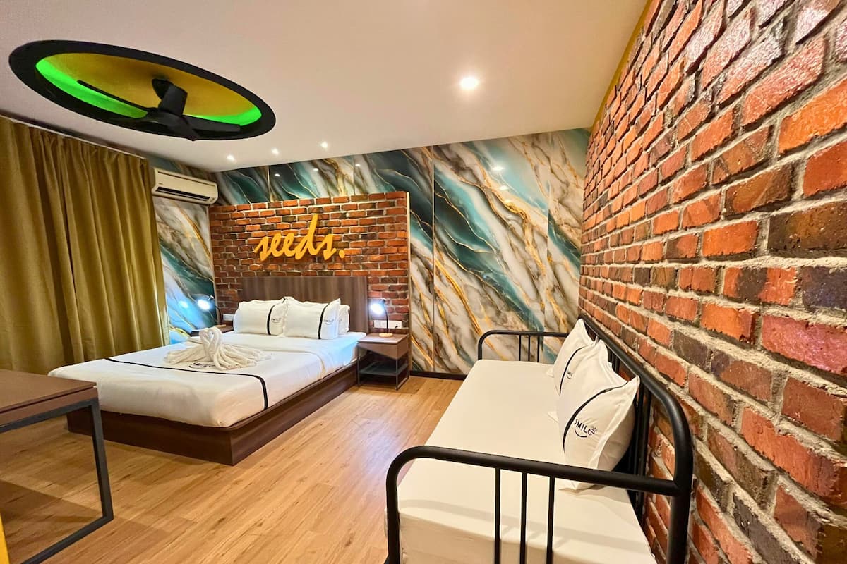 Une chambre d’hôtel avec un mur en briques, une fresque murale, un lit avec une literie blanche, une table de chevet et un bureau.