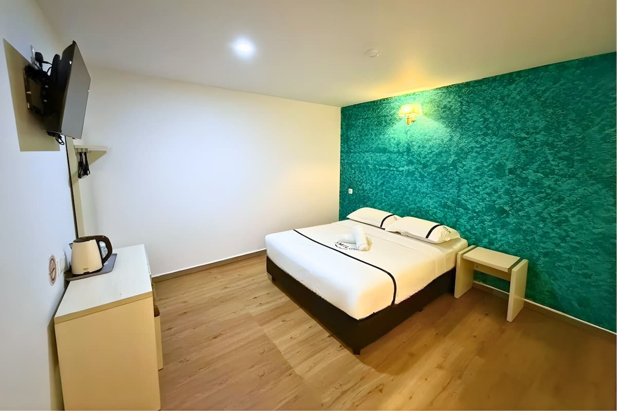 Une chambre d’hôtel avec un lit, une table de chevet et un mur vert à texture.