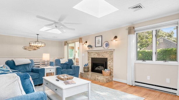 Un salon avec une cheminée, des canapés bleus, une table basse blanche et un ventilateur de plafond.