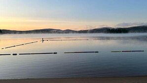 Un lago tranquilo con muelles flotantes y montañas brumosas al fondo.