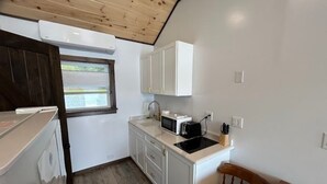 A compact kitchen with white cabinets, a microwave, a toaster, and a sink.