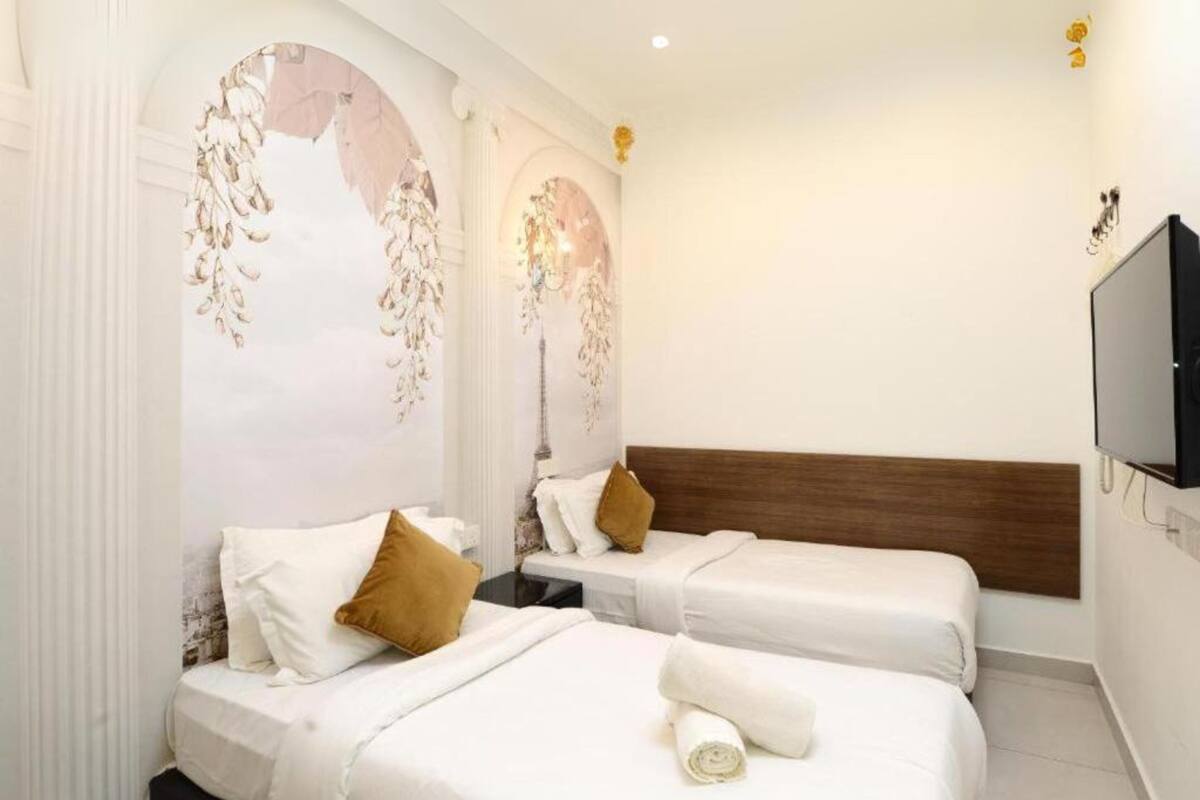 A hotel room with two beds, a wooden headboard, a television, and decorative wall art.