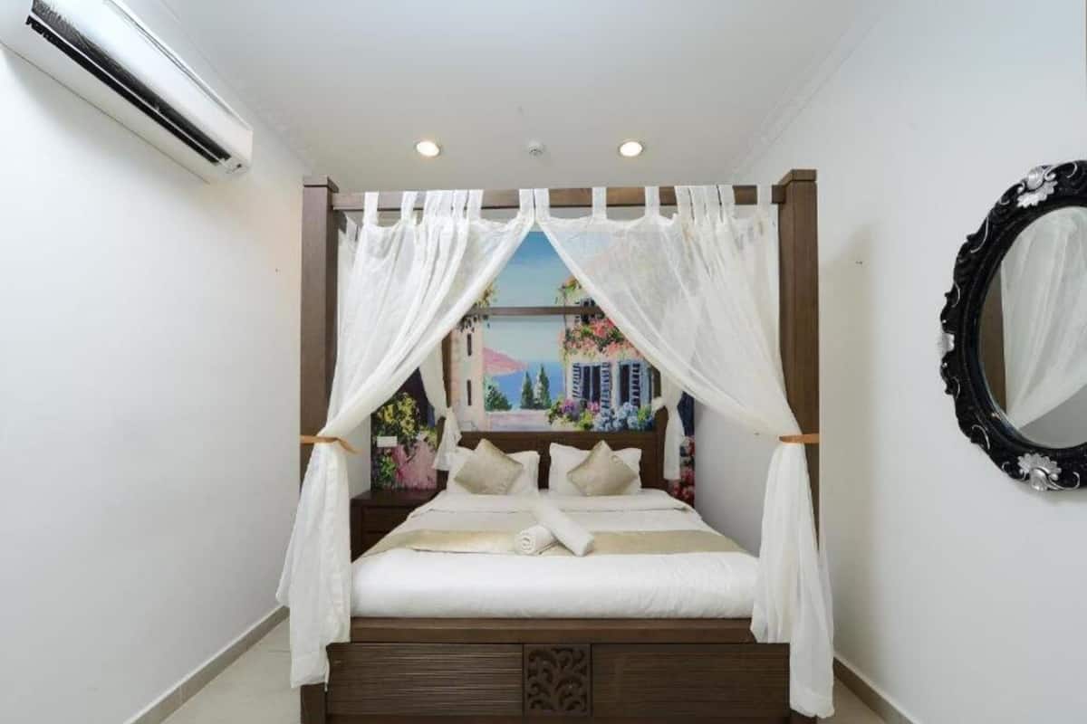 A bedroom with a bed under a canopy, a wall-mounted mirror, and a painting of a cityscape.