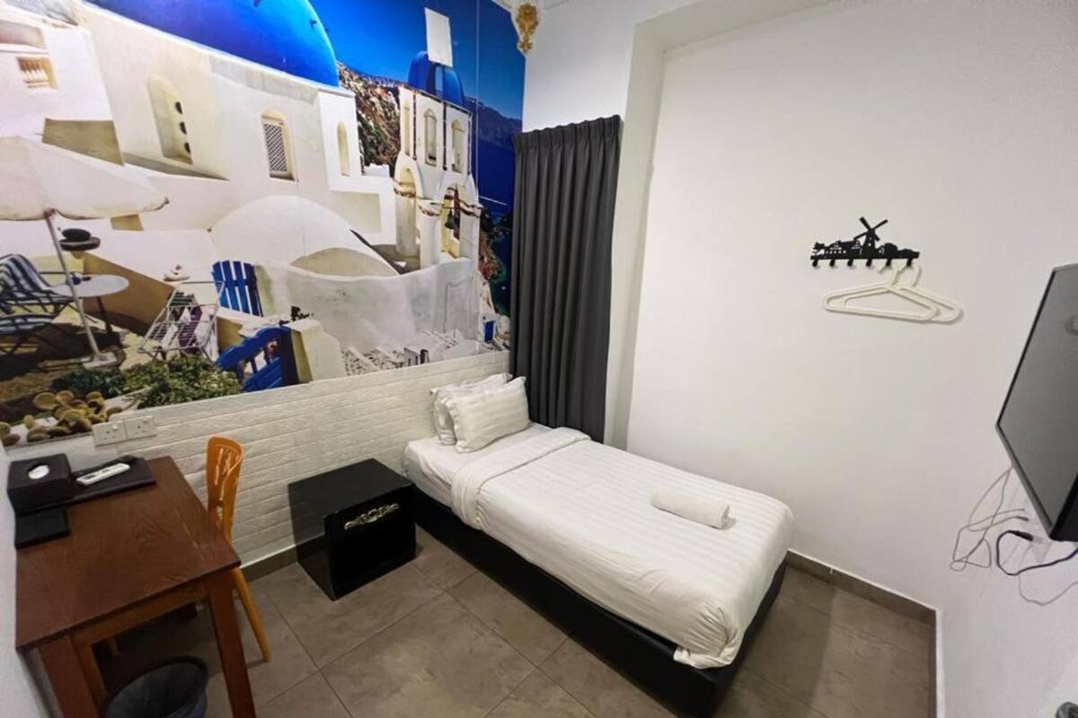 A compact hotel room with a bed, a desk, and a chair.