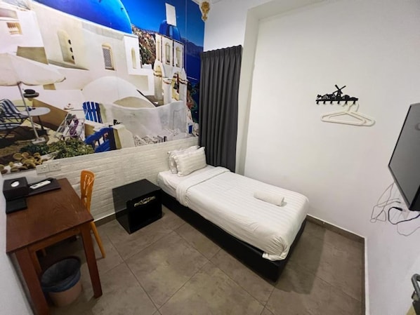 Una habitación de hotel pequeña con una cama, un escritorio y una silla.