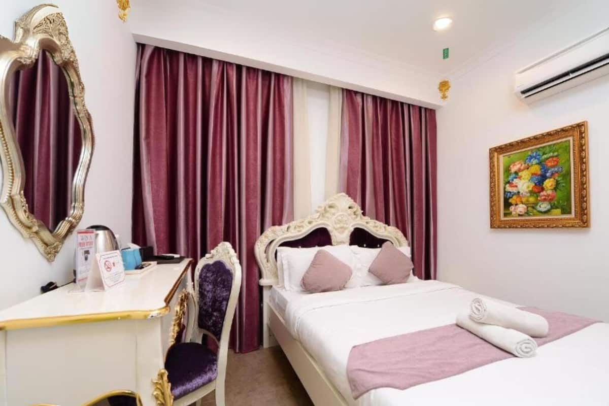 A hotel room with a bed, a desk, a chair, a mirror, and a painting on the wall.