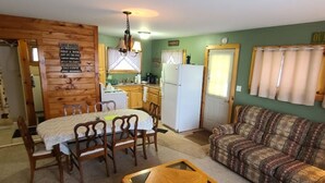 Un espacio habitable compacto con comedor, sofá, una mesita y zona de cocina.
