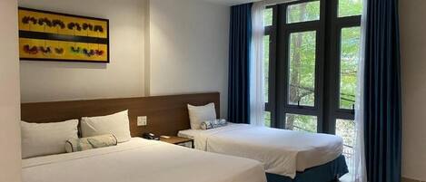 Habitación de hotel con dos camas, un ventanal con cortinas y un cuadro en la pared.