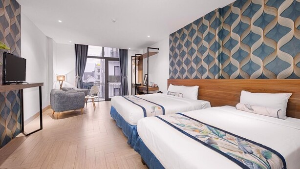 Een hotelkamer met twee bedden, een televisie, een bureau en uitzicht op de stad.