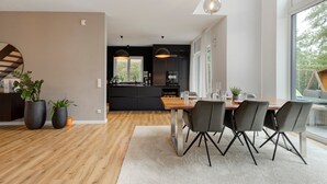 A modern kitchen with dark cabinetry, a wooden dining table, and black chairs. - Holiday Home 'Luxurious Family House' with Terrace and Wi-Fi (Tornesch)