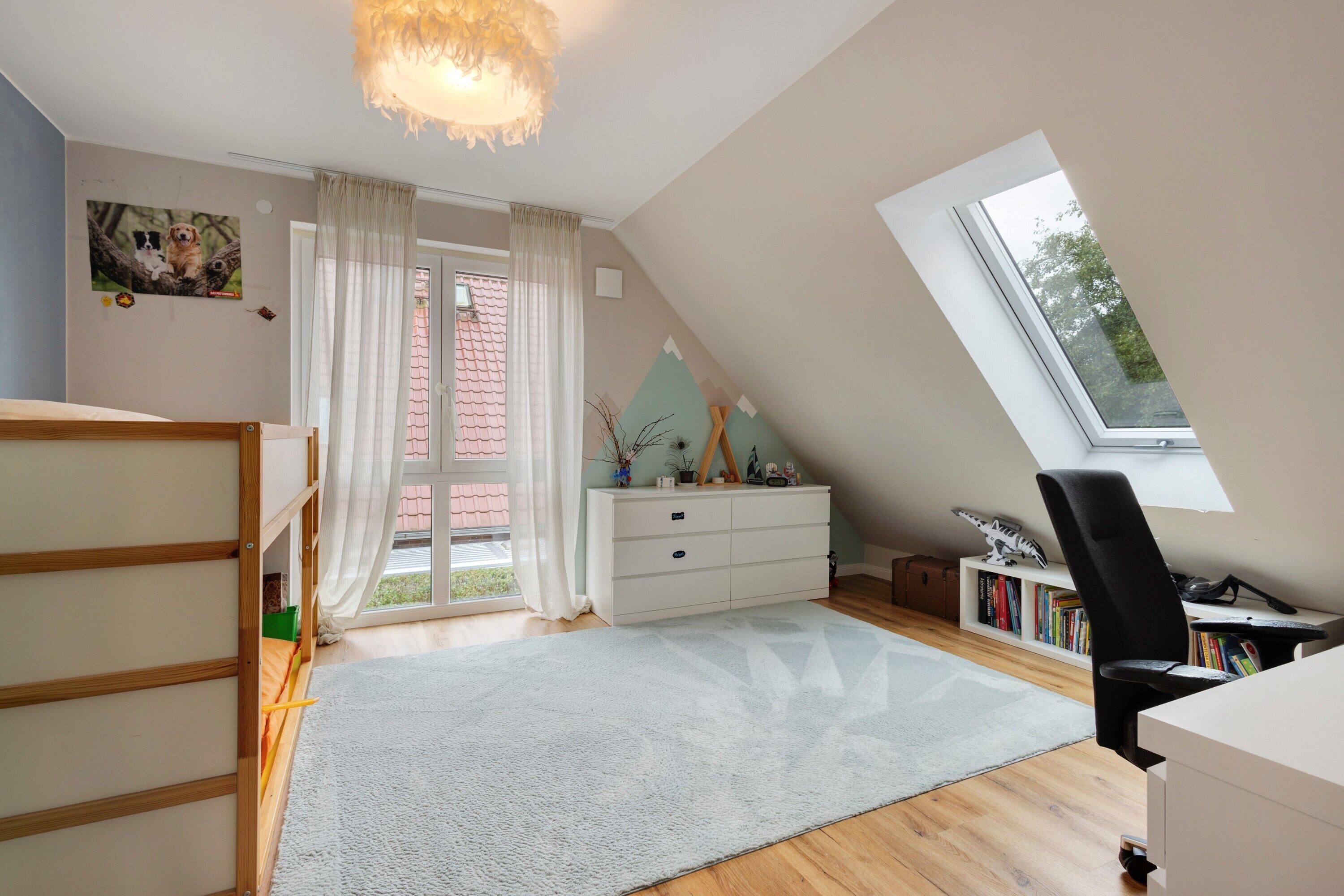 A room with a bunk bed, a desk with a chair, a bookshelf, and a window.