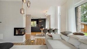 A modern living room with a sofa, dining table, and kitchen in the background. - Holiday Home 'Luxurious Family House' with Terrace and Wi-Fi (Tornesch)