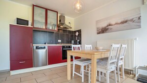 Una cocina con mesa y sillas, microondas, cafetera y radiador.
