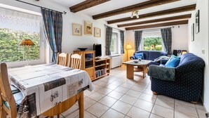 A living room with a dining table, sofa, and bookshelf. - Apartment 'Haus Schröder' with Shared Terrace, Shared Garden and Wi-Fi (Sankt Michaelisdonn)