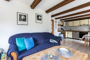 Una sala de estar con un sofá, una mesa de comedor y una cocina al fondo.
