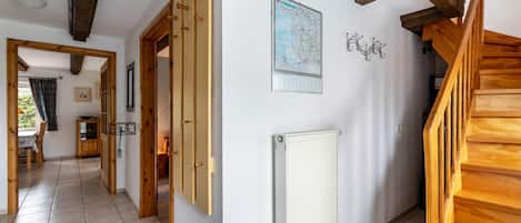 A hallway with wooden doors, a radiator, a map on the wall, and a staircase.