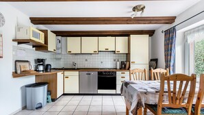 A compact kitchen with wooden cabinets, a dishwasher, and a dining table with chairs. - Apartment 'Haus Schröder' with Shared Terrace, Shared Garden and Wi-Fi (Sankt Michaelisdonn)