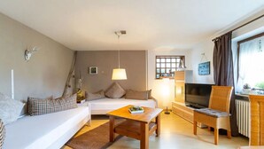 Ein Wohnzimmer mit Sofa, Couchtisch, Fernseher und einem Sessel.