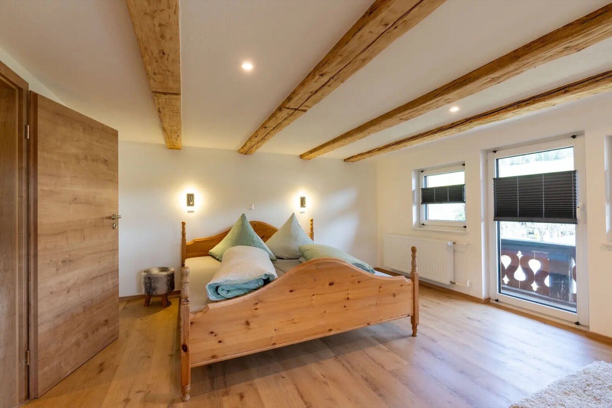 Un dormitorio con una cama de madera, dos lámparas de noche, un radiador y una ventana con persianas.