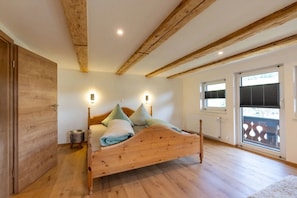 A bedroom with a wooden bed, two bedside lamps, a radiator, and a window with blinds.