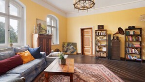 A room with a sofa, a coffee table, a bookshelf, and a door. - Apartment 'Wohnen Im Alten Rittergut' with Private Terrace, Garden & Wi-Fi (Calau)