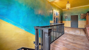 A staircase with a wooden railing, a chandelier, and a door with a sign. - Apartment 'Wohnen Im Alten Rittergut' with Private Terrace, Garden & Wi-Fi (Calau)