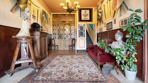 A hallway with a chandelier, a statue, a red sofa, a potted plant, and a staircase. - Apartment 'Wohnen Im Alten Rittergut' with Private Terrace, Garden & Wi-Fi (Calau)