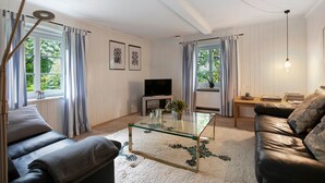 A living room with a glass coffee table, leather sofa, and a television.