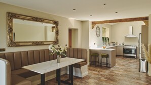 A modern living room with a brown leather sofa, a white table, and a large ornate mirror. - Rye Top Farm - Luxury Cottages (Uppermill)