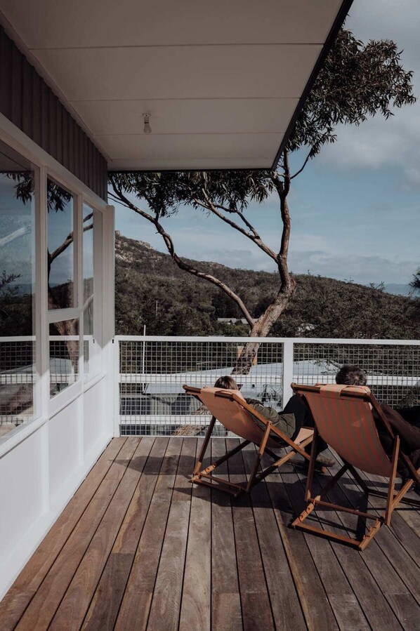 A wooden deck with two rocking chairs and a view of a mountainous landscape.