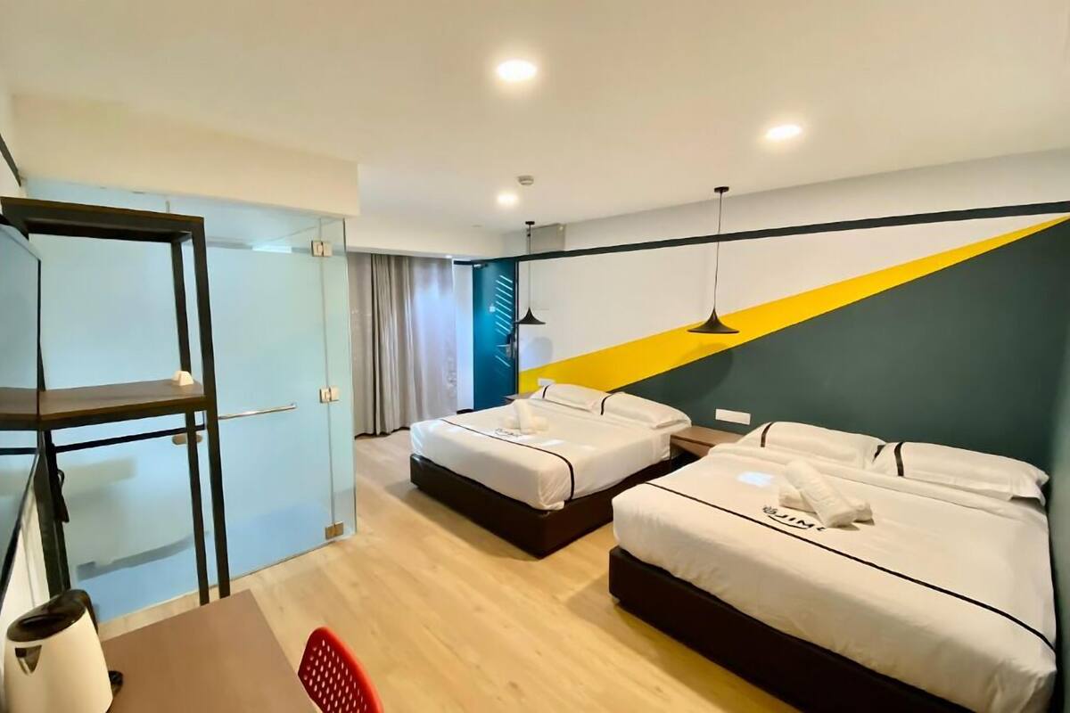 Een hotelkamer met twee bedden, een bureau, een stoel en een glazen scheiding.