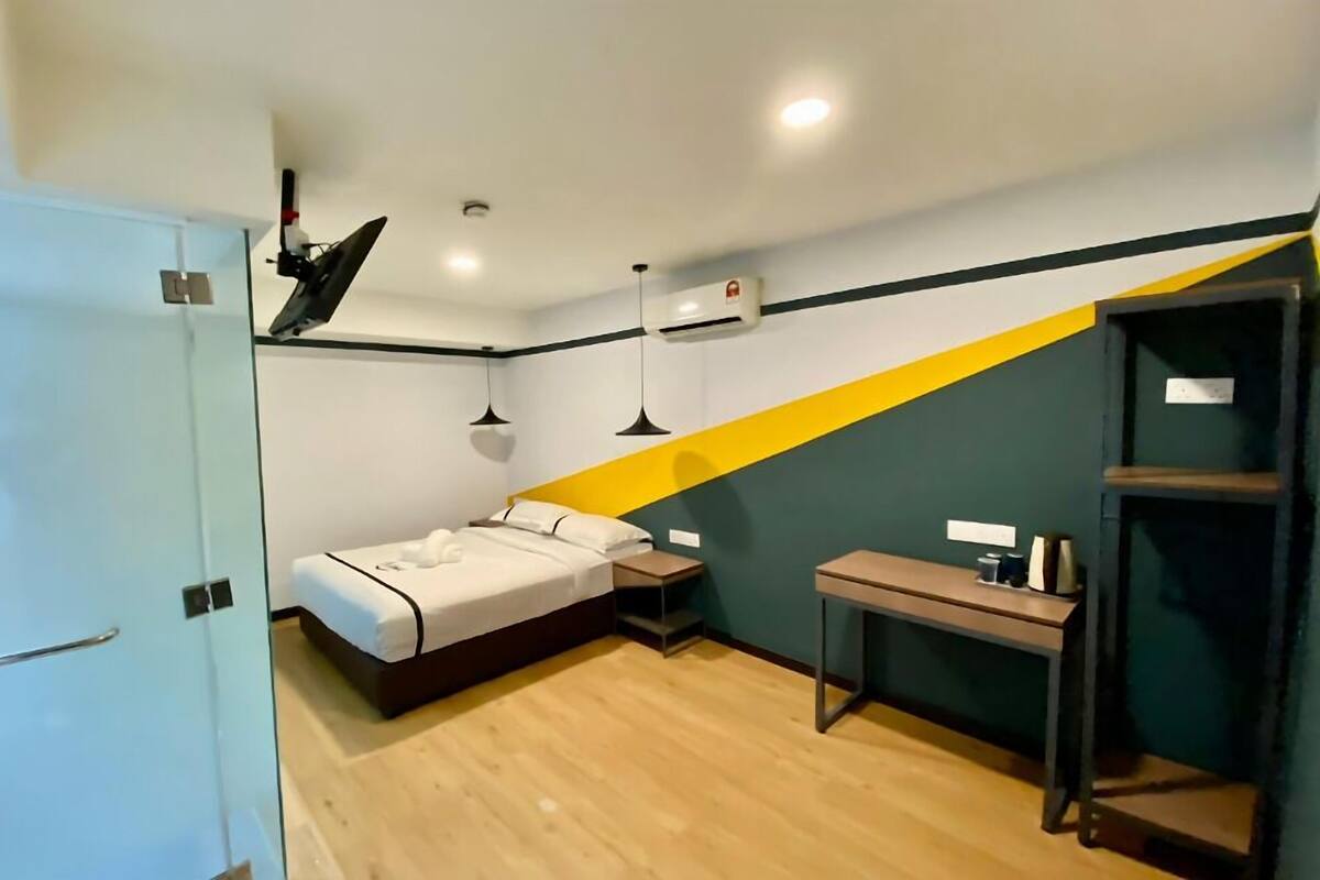 Een kleine hotelkamer met een bed, nachtkastje en bureau.