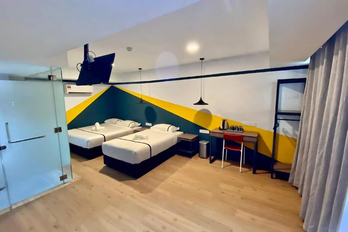 Een moderne hotelkamer met twee bedden, een klein bureau, een stoel en een televisie.