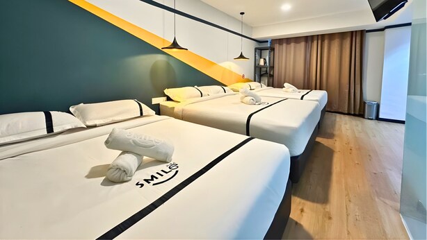 Ein Hotelzimmer mit zwei Betten, einem an der Wand montierten Fernseher und einer Treppe mit gelbem Akzent.