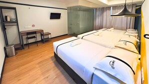 Ein Hotelzimmer mit zwei Betten, einem Schreibtisch, einem Stuhl, einem Fernseher und einer Duschkabine.